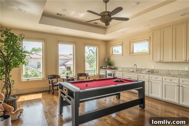 The spacious upstairs game room features a well-appointed wet bar and extensive built-ins, with direct access to the expansive outdoor terrace, making it an ideal hub for entertainment.