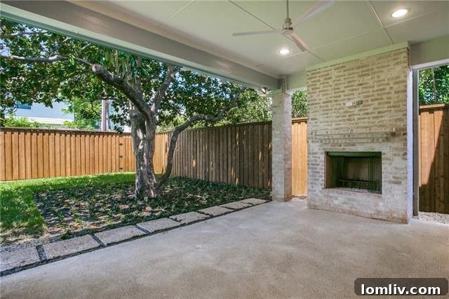 Spacious covered patio with outdoor fireplace and ceiling fan, perfect for entertaining.