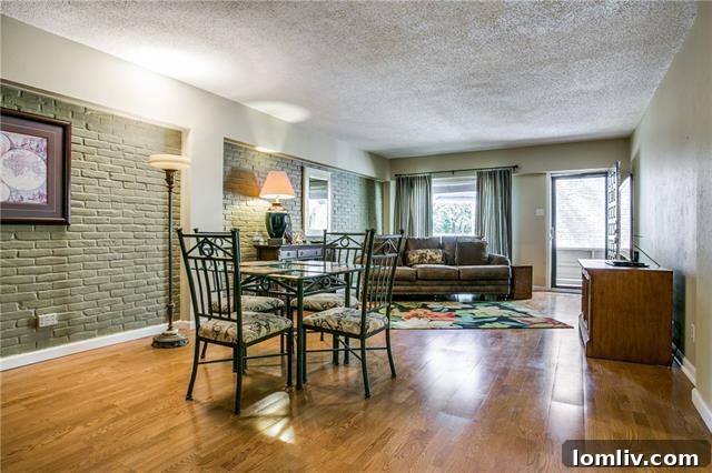 The spacious living and dining area of Unit 204 at Turtle Creek Gardens, featuring exposed brick and abundant natural light.