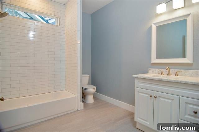 Elegantly designed guest bathroom featuring floor-to-ceiling subway tiles, a chic marble sink vanity, and modern fixtures