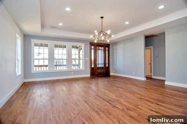 Bright and spacious open-concept living and dining area, ideal for entertaining, featuring high tray ceilings and polished hardwood floors