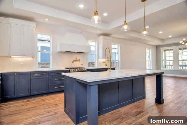 Contemporary kitchen with rich navy lower cabinets, pristine white upper cabinets, marble countertops, and a large island, ready for gourmet cooking