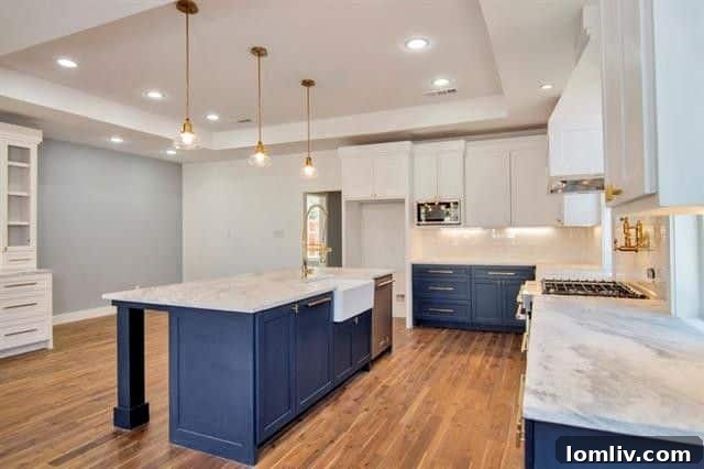 Close-up of the elegant marble island and countertops in the kitchen, highlighting the gold-tone hardware on the pristine white cabinetry