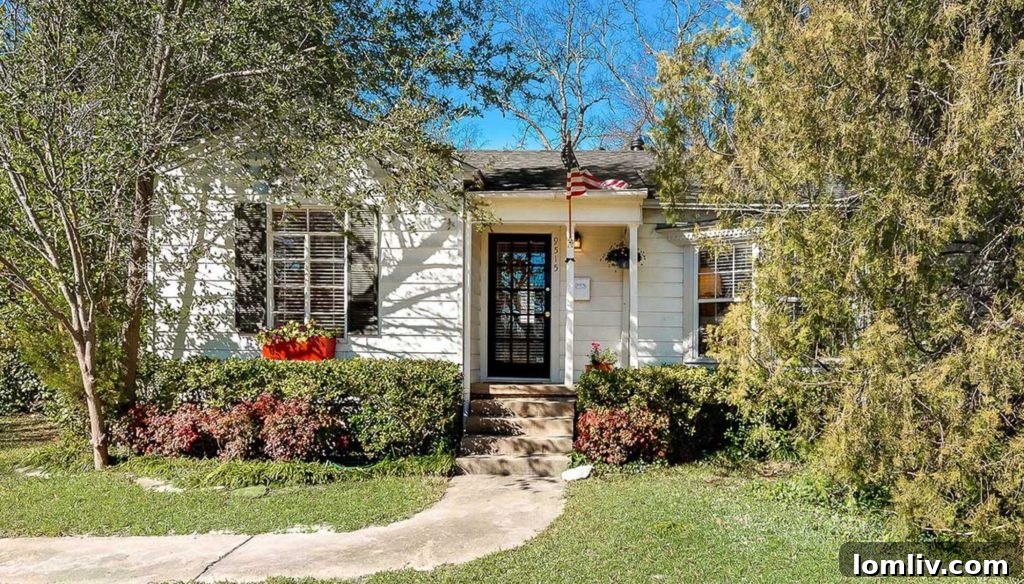 A charming mid-century home in Old Lake Highlands, Dallas, with a green lawn and mature trees, featuring a 'For Sale' sign.