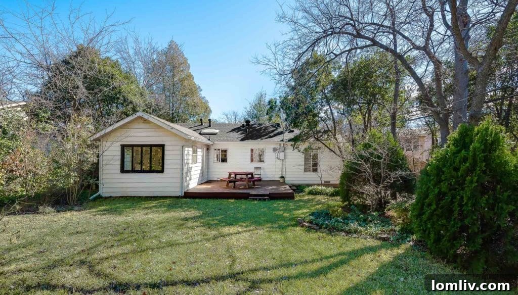 Spacious backyard of the Old Lake Highlands home with a wooden deck and mature trees.