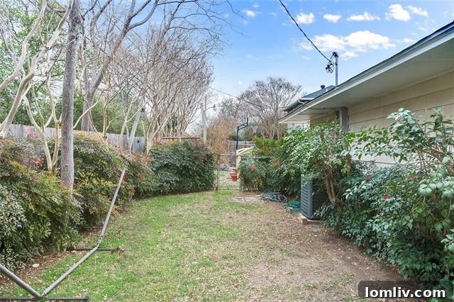 Expansive backyard with a lush side lawn and vibrant crepe myrtles, ideal for outdoor activities.