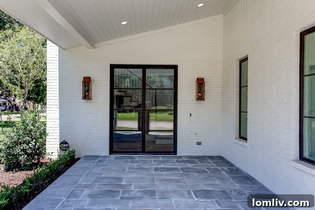 Grand entrance of 700 N. Bailey, featuring a spacious porch with blue flagstone, elegant gas coach lamps, and a robust steel door from Durango Doors, symbolizing premium new construction in Fort Worth.