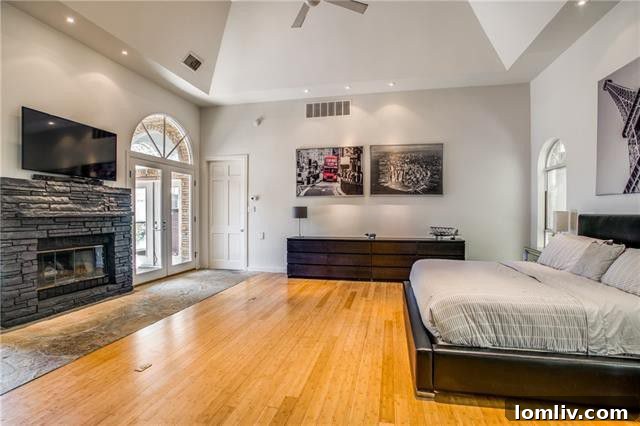 Spacious Oak Cliff Contemporary: Built for Bliss, Designed for Downtime 7 The grand master bedroom at 731 Kessler Lake Drive, featuring dramatic vaulted ceilings, a cozy stone hearth fireplace, and direct patio access.