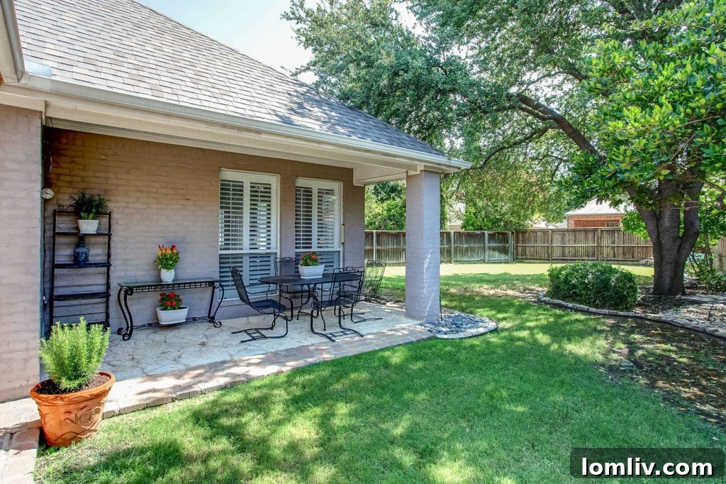 Enjoy the serene stone patio and majestic trees at this beautiful Stonegate home, perfect for outdoor living and relaxation.