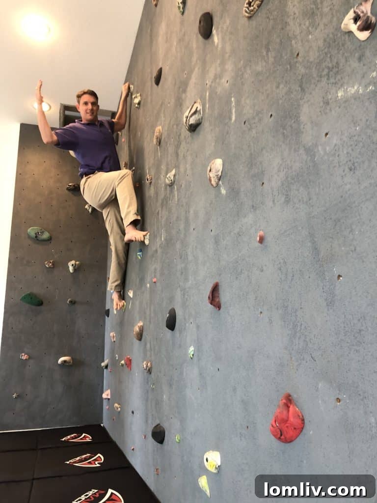 A realtor demonstrates the impressive climbing wall feature at 2885 Oakbriar Trail in Stonegate, Fort Worth, highlighting its unique recreational appeal.