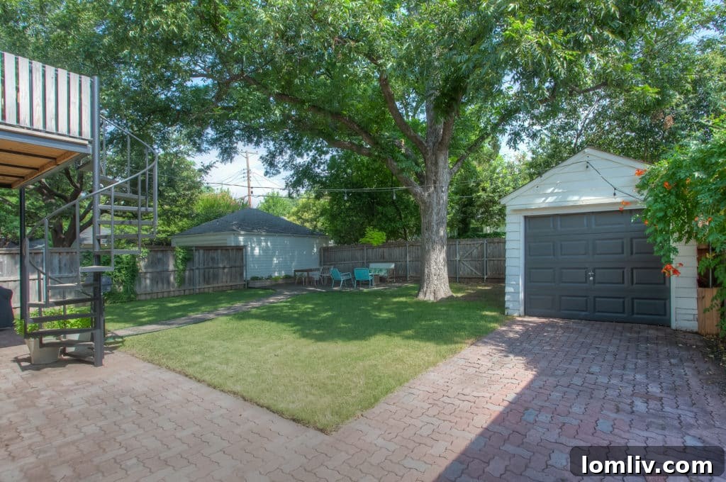 Charming backyard with mature shade trees and an attractive paver driveway, enhancing outdoor living.