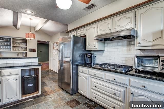 Modern updated kitchen with granite countertops and white subway tile backsplash at 9447 Viewside Drive.