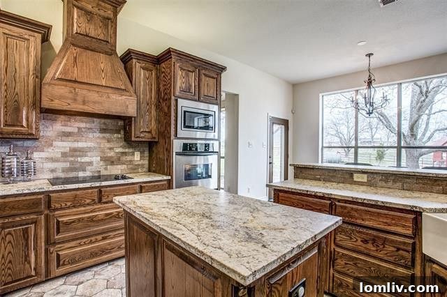 Modern kitchen with elegant granite countertops, custom wood cabinets, and high-end stainless steel appliances, including a double oven.