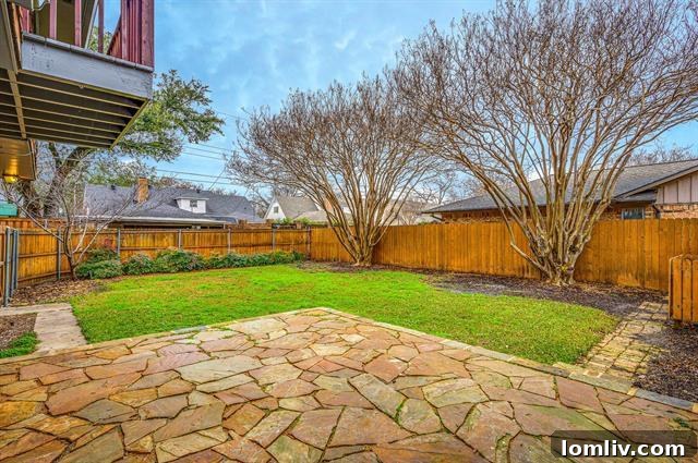 Vibrant backyard with a stone patio, ideal for outdoor barbecues, family gatherings, and enjoying the Dallas sunshine.