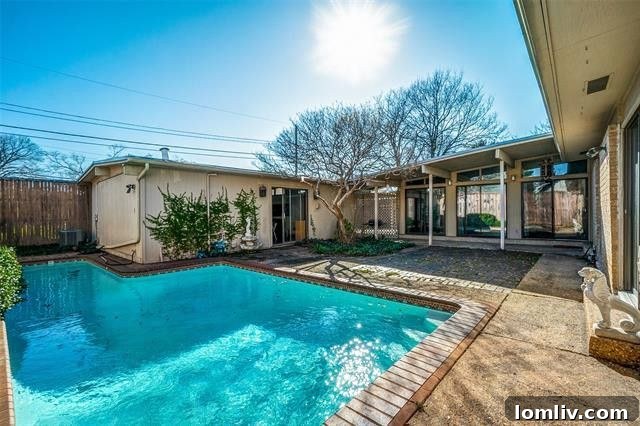 Inviting backyard of the Ju-Nel designed property, featuring a stunning crystal blue swimming pool and a detached pool house, perfect for entertaining.