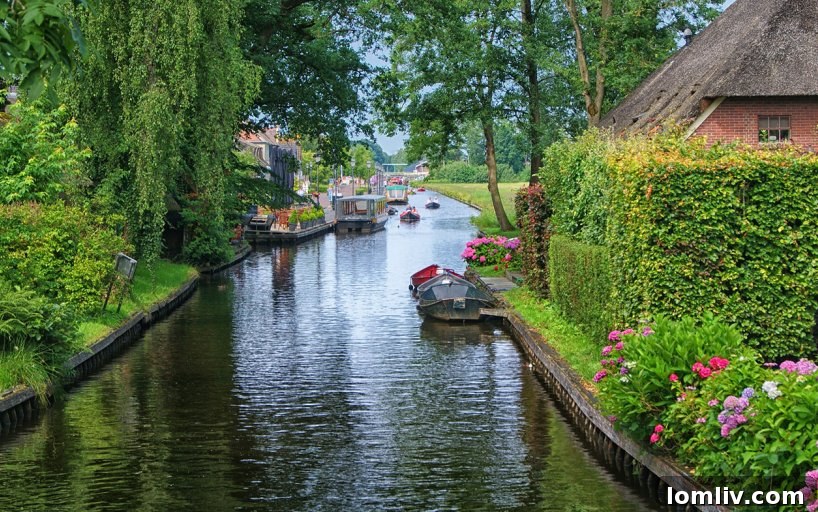 Scenic view of Giethoorn with a bridge over a canal leading to a thatched house