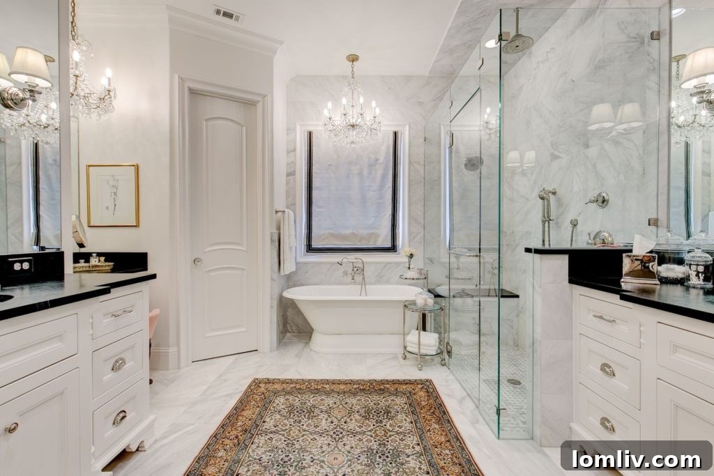 Spa-like master bathroom with twin vanities, large shower, slipper tub, and black and white marble