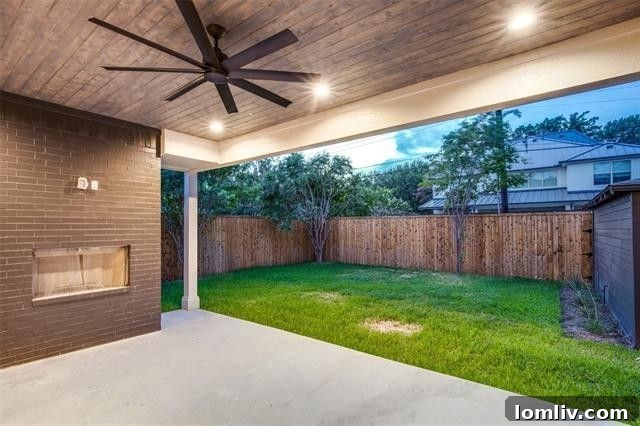 Inviting outdoor living area with a cozy wood-burning fireplace, overlooking a lush, private backyard in a Dallas home.