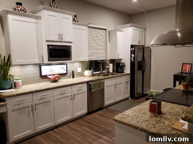 A renovated kitchen with bright white paint on cabinets, harmonizing with existing countertops and backsplash.