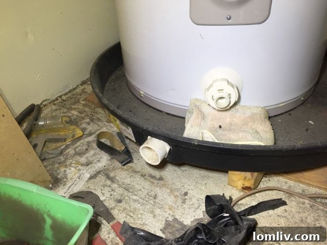 An overflowing water heater drain pan with a towel soaking up water, indicating a leak and improper drainage.
