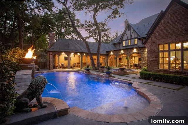 Outdoor fireplace beautifully illuminating a swimming pool at night, offering a magical ambiance for evening enjoyment at 2925 Owenwood Drive.