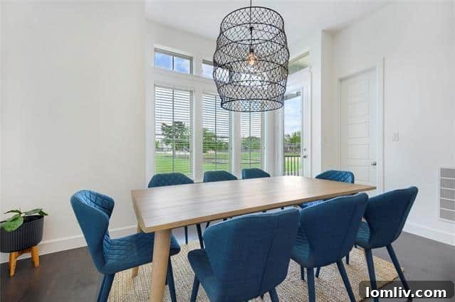Modern dining area seamlessly connected to the kitchen island and living space, featuring contemporary lighting.