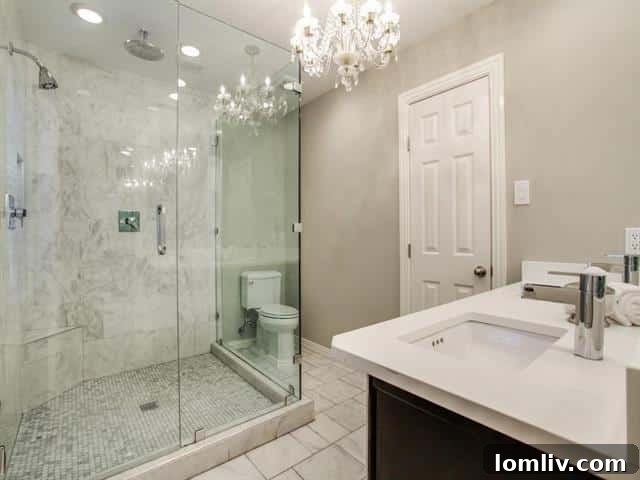 The luxurious spa-like master bathroom, complete with marble floors, a rainfall shower, and another exquisite crystal chandelier.