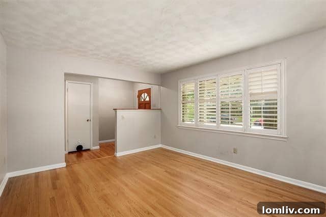 The spacious and inviting living room of the Buckner Terrace home, featuring original hardwood floors and ample natural light. A perfect blend of comfort and style.