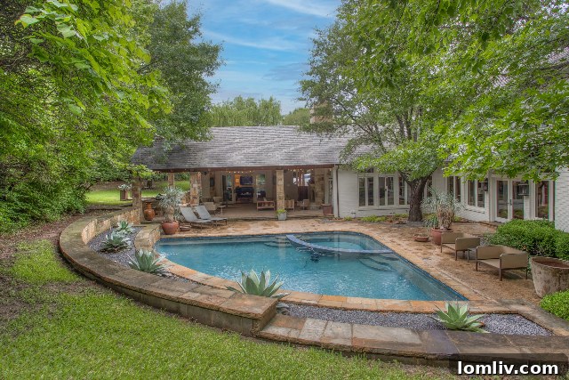 Shaded outdoor entertaining area next to a sparkling swimming pool in a Fort Worth luxury property