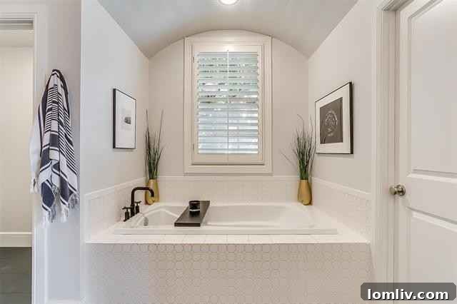 The ground-floor primary suite features a luxurious ensuite bath with twin sinks, a spacious shower, and an inviting under-arch garden tub.