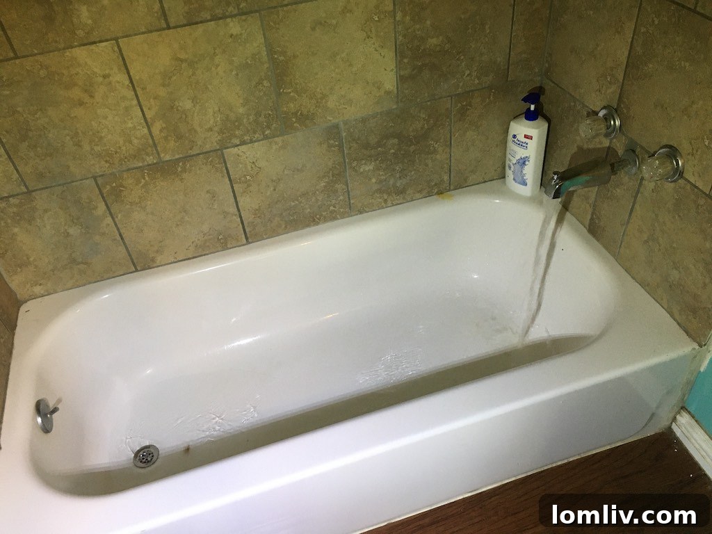 Bathtub with faucet and drain positioned at the foot end, facing the wall, indicating an incorrect installation
