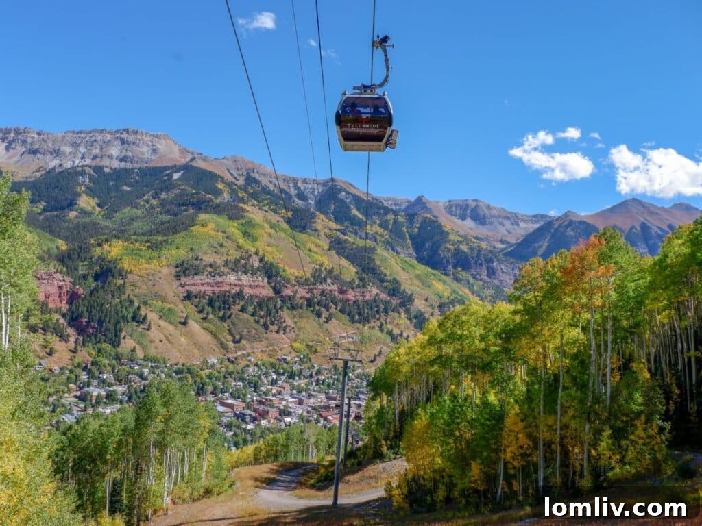 Scenic view of Telluride Gondola transporting skiers and sightseers against a backdrop of snow-capped mountains and evergreen trees
