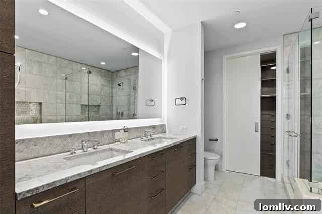 Luxurious marble primary bathroom with dual sinks and backlit mirror