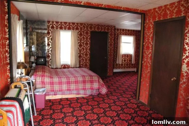 A bedroom with a patterned bedspread, dark wood furniture, and a general feeling of comfort and history.
