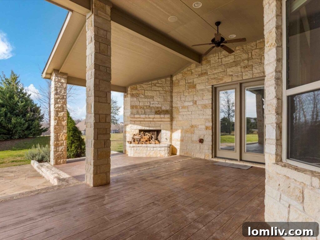 Cozy covered back porch with a built-in fireplace overlooking the expansive backyard