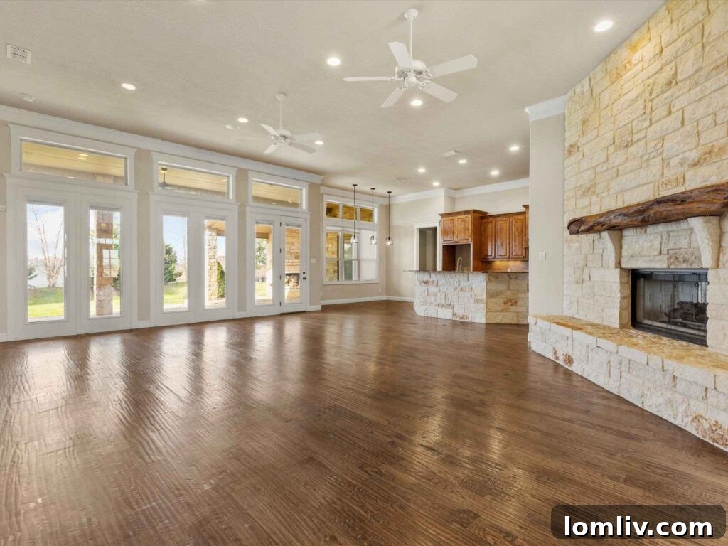 Spacious open-concept living room with angled stone fireplace and hardwood floors