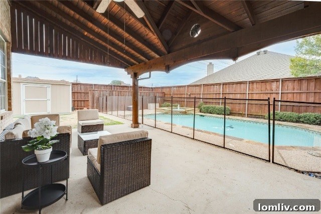 Spacious backyard featuring a sparkling swimming pool with a safety fence and lush green lawn
