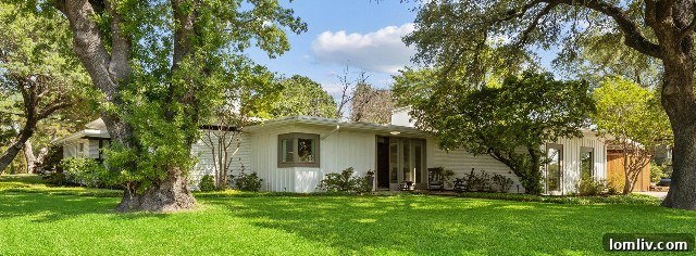 Front exterior of 4700 Winthrop Avenue West Midcentury Modern home surrounded by trees