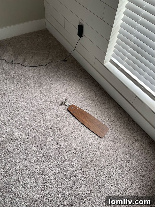 A second view of a detached ceiling fan blade, emphasizing the danger of loose fixtures.