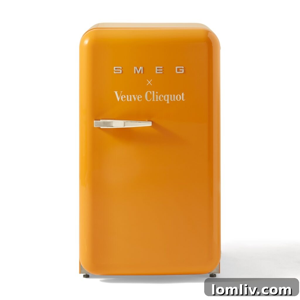 The Ultimate Holiday Gift Guide 5 A stylish Smeg Veuve Clicquot Refrigerator in a vibrant orange hue, showcasing its retro design and sleek finish.