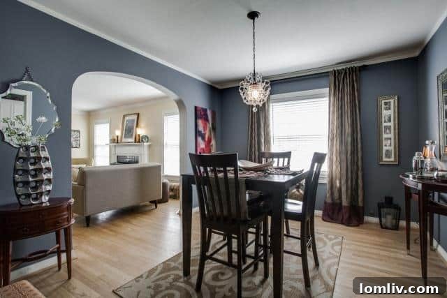 Dining room at 2531 W 10th Street with a modern chandelier, dark blue walls, and original hardwood floors