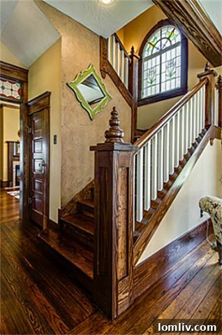 Grand wooden staircase inside 2113 Mangum, showcasing intricate balusters, polished wood finishes, and a graceful curve, serving as a prominent architectural feature of this historic home.