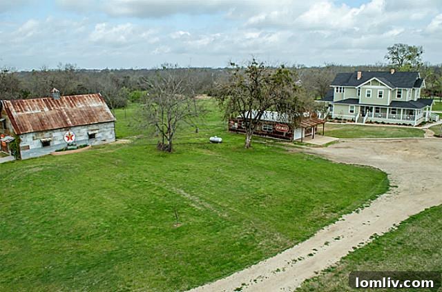 Aerial view of the expansive 3.5-acre property at 2113 Mangum, Commerce, TX, highlighting the main house, diverse outbuildings, and surrounding lush landscape, demonstrating its ample space and privacy.