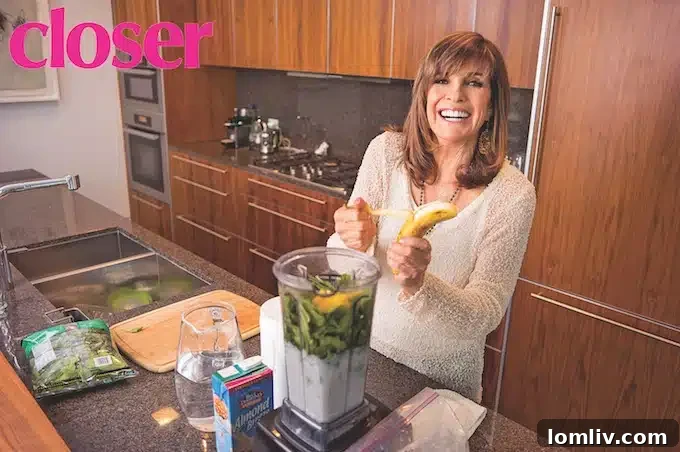 Linda Gray in a bright, open-plan living area of her condo, showcasing modern furniture, art, and abundant natural light.