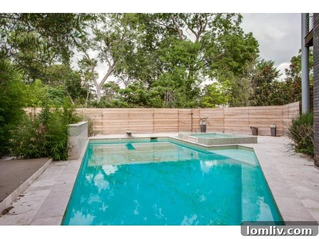 Luxury backyard pool and hot tub area with stone paving and privacy fencing