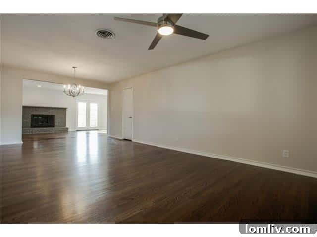 Interior view of the open-concept living room flowing into the den with a brick fireplace