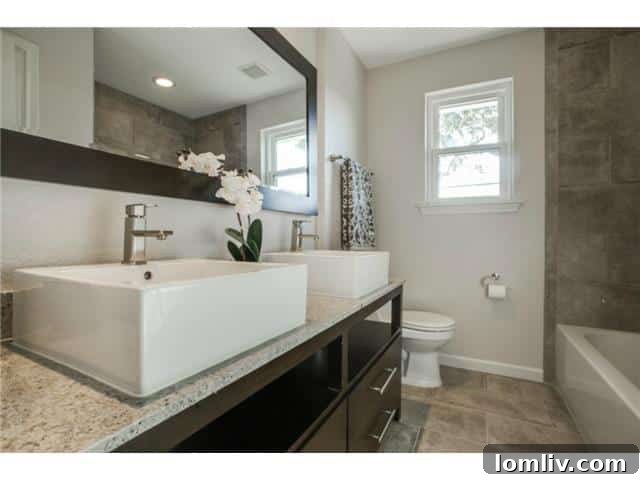Renovated hallway bathroom with porcelain tiles, double vessel sinks, and modern vanity