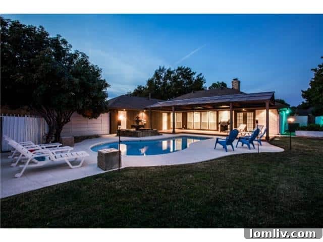 Panoramic view of the private backyard oasis with pool and water features in Richardson home