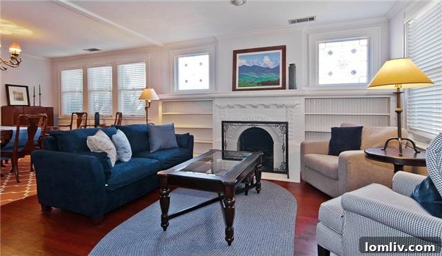 Historic North Oak Cliff Tudor: Stained Glass and Chambers Stove Legacy 5 Bright living room interior of 1325 Hollywood Ave, showcasing gleaming hardwood floors and a traditional fireplace
