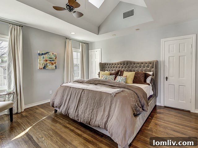 Luxurious master bedroom with a tufted headboard, elegant recessed lighting, and warm color palette